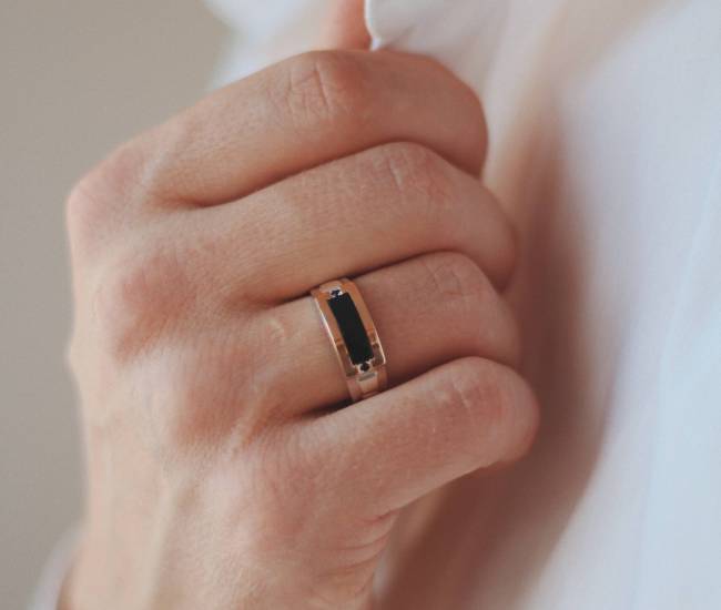 A closeup shot of a male in a formal outfit wearing a golden ring